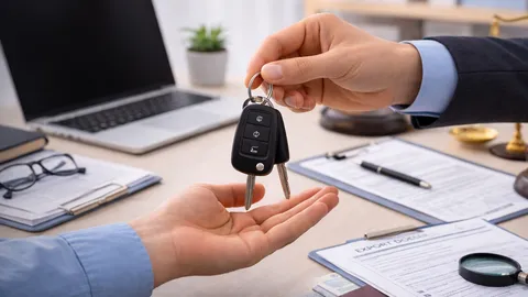 Ein Autoschlüssel wird über einem Schreibtisch mit Exportunterlagen und einer Lupe übergeben