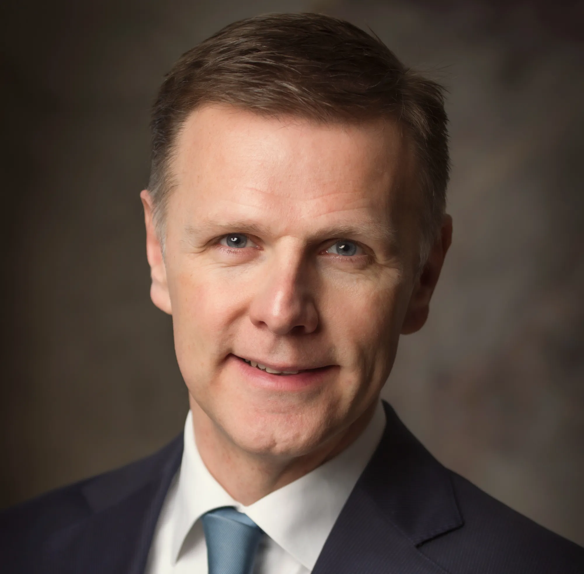 Portret van Michel van Roon in een donker pak met lichtblauwe stropdas