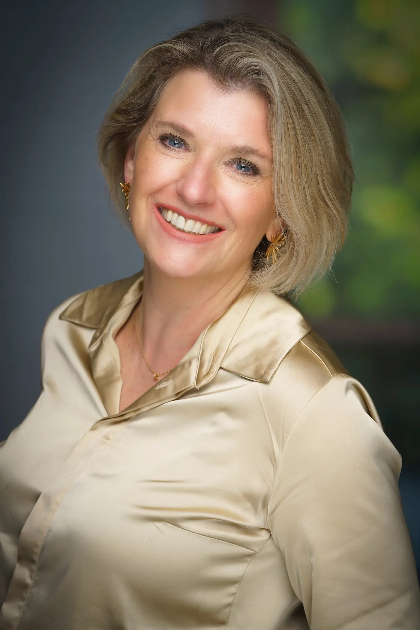 Portrait of Sabine Orgelist, smiling, in a champagne-colored blouse